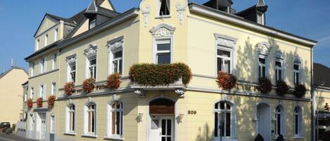 A yellow building with a classic architectural style, featuring a central entrance with a door and windows on the upper floors.