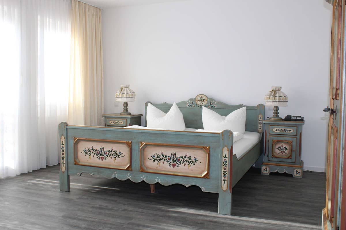 A bedroom with a bed, two nightstands, and a window with curtains.