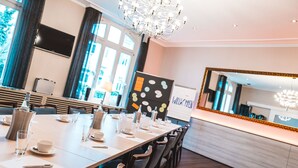 Ein moderner Konferenzraum mit einem langen Tisch, Stühlen, einer Kandelaber und einem großen Spiegel.