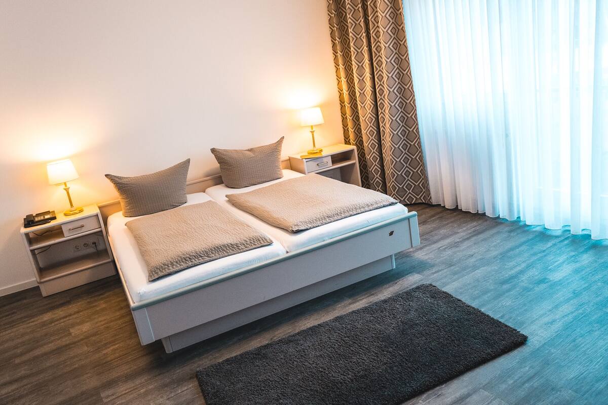 A modern bedroom with a bed, two bedside tables, a lamp, and a rug.