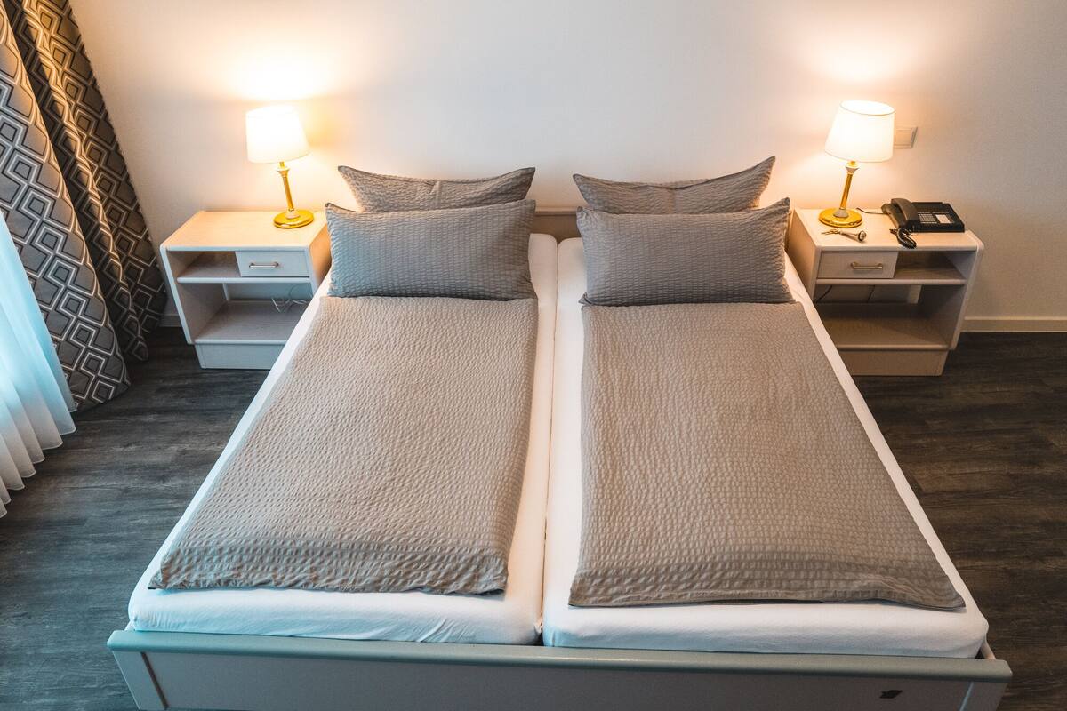 A double bed with two bedside tables, each with a lamp and a phone.