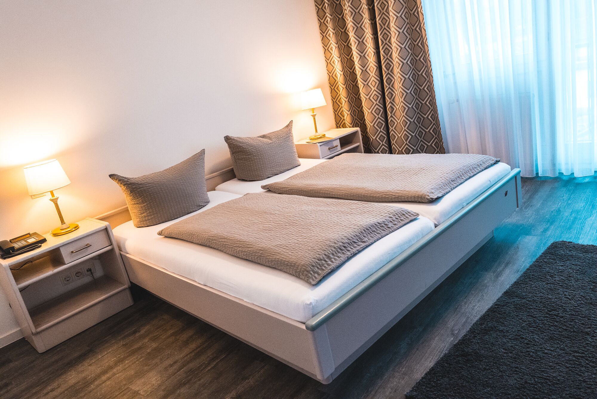 Un lit double avec deux oreillers, une table de chevet avec une lampe et une petite table de nuit avec un téléphone.