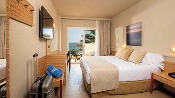 Habitación de hotel con cama, escritorio, silla, televisión y vista al océano.