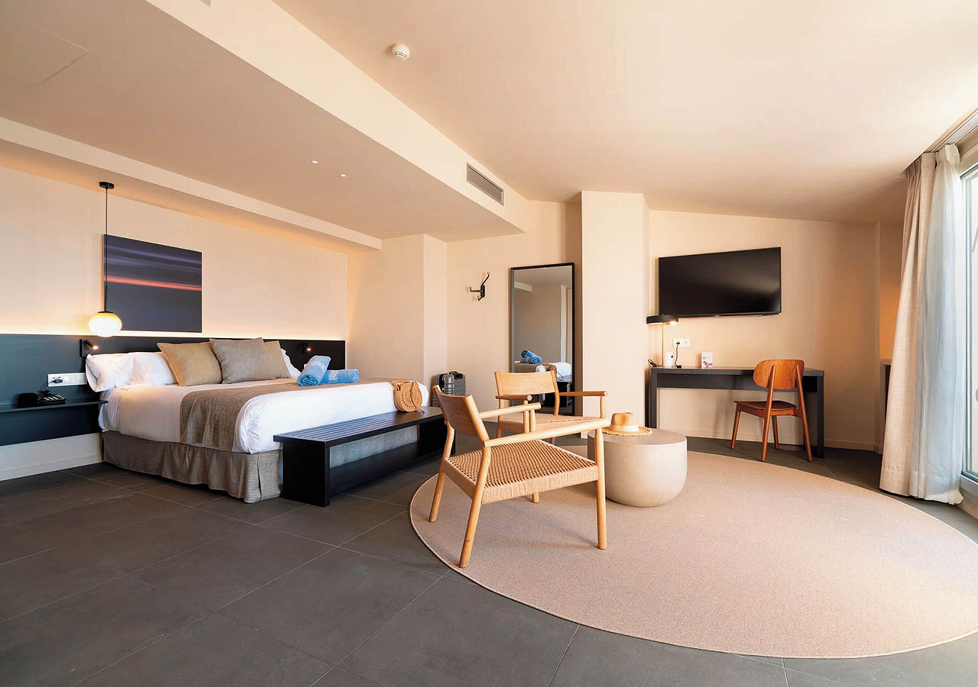 Una habitación de hotel moderna con una cama, un escritorio, una silla y un televisor.