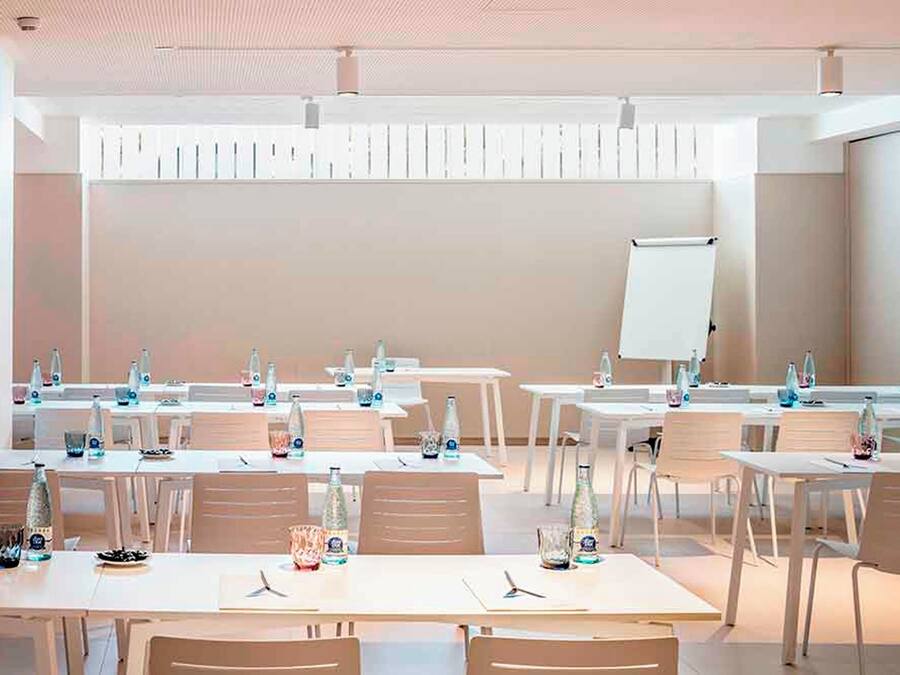 Un salón de conferencias con varias mesas, sillas y una pizarra.