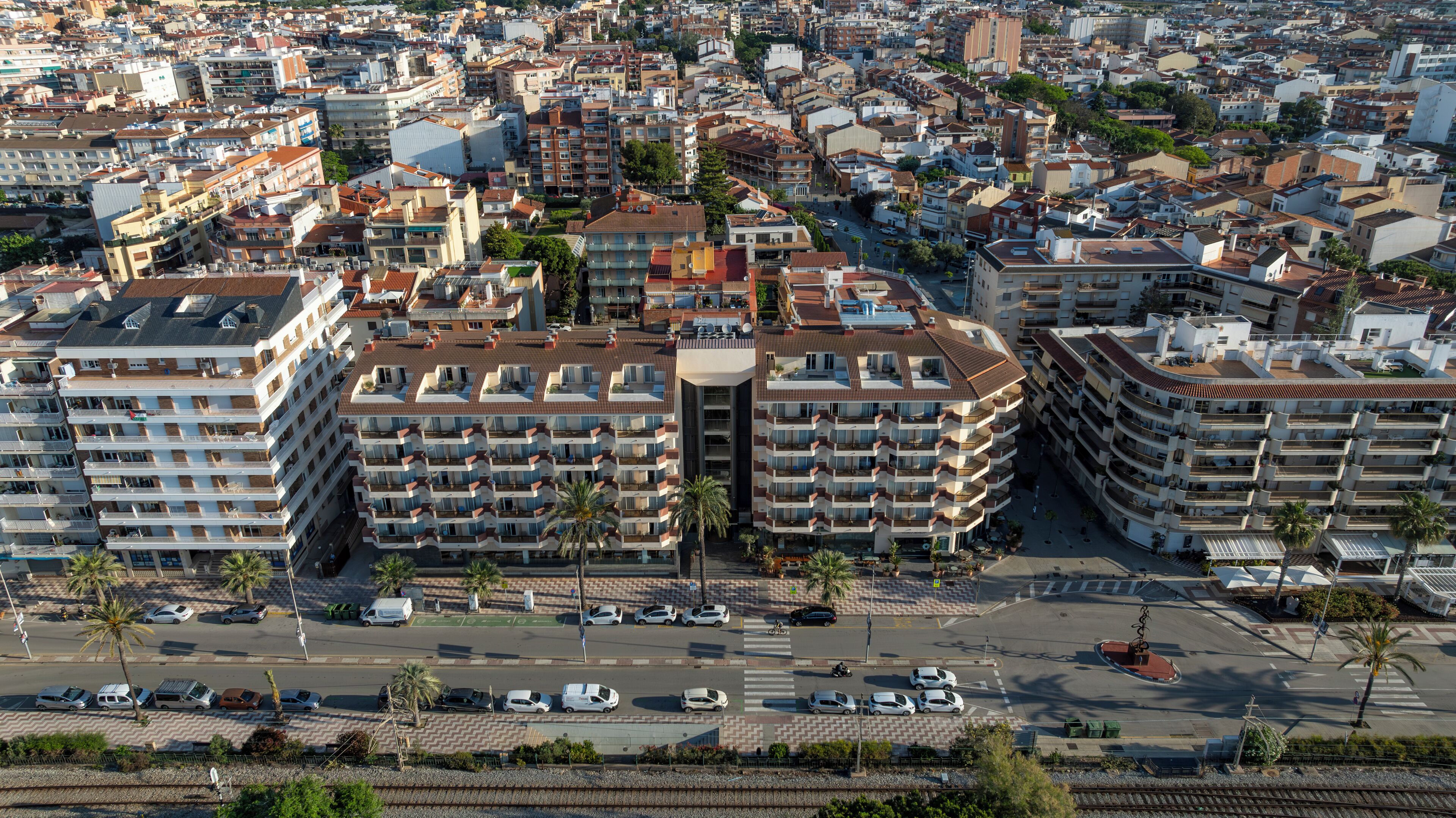 Ein Hochhaus-Hotel mit mehreren Balkonen, einem Innenhof und einem Parkplatz mit Autos.