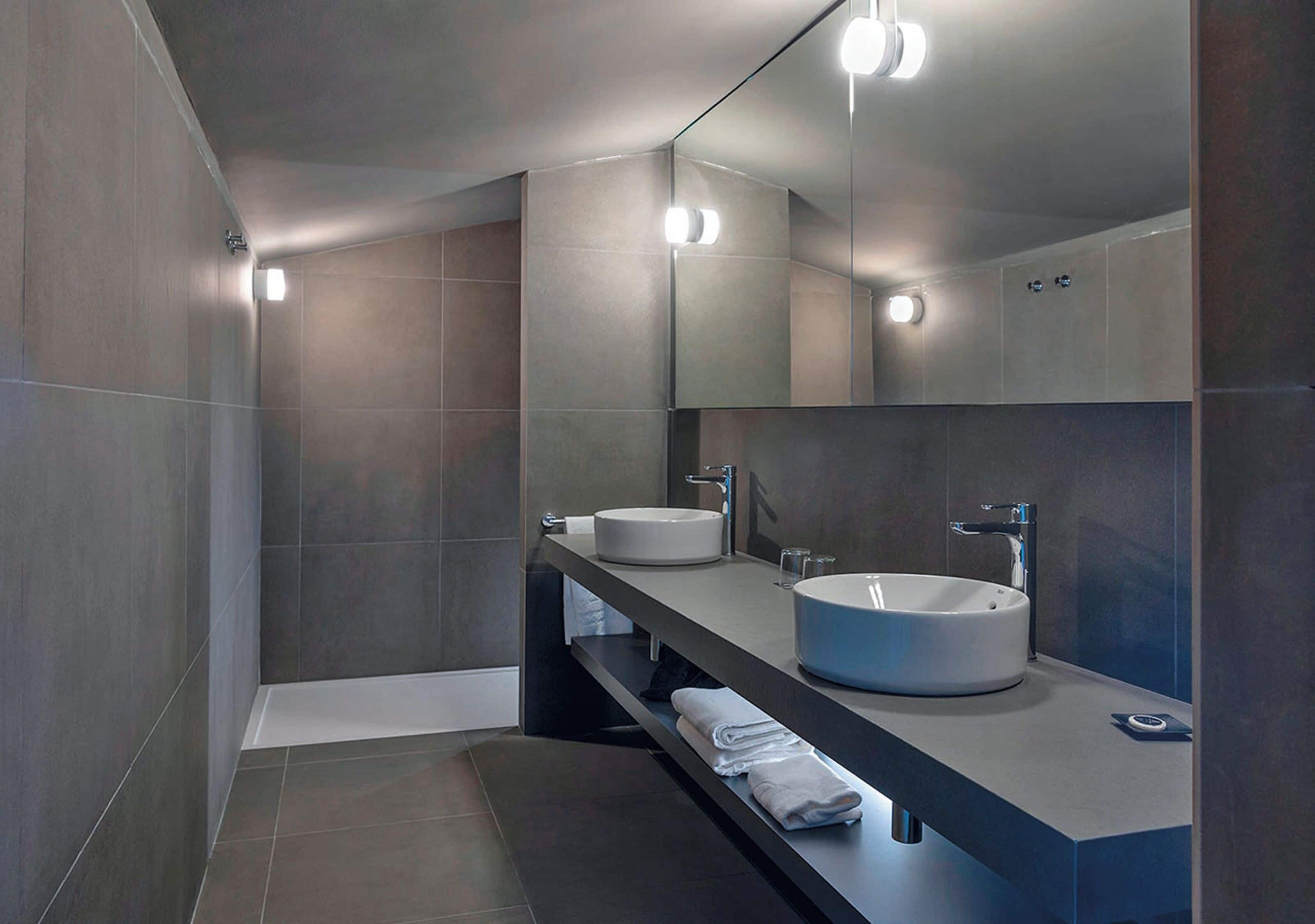 Un baño moderno con dos lavamanos, un espejo grande e iluminación empotrada.