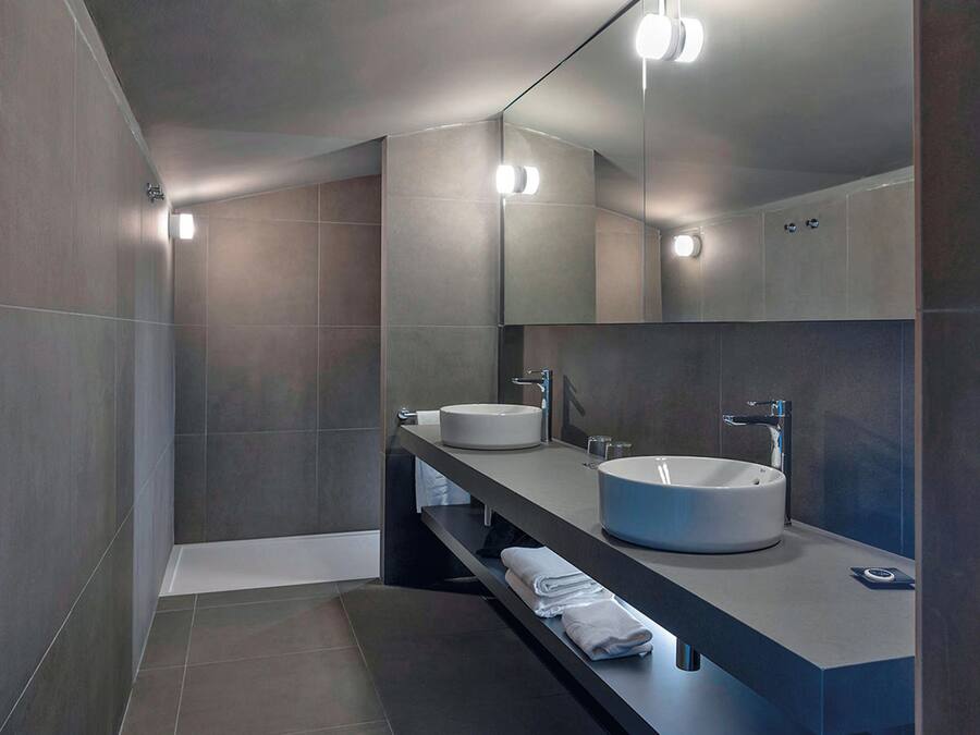 Un baño moderno con dos lavamanos, un espejo grande e iluminación empotrada.