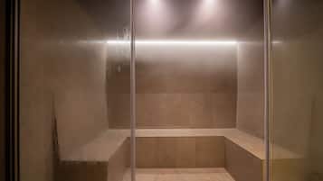 Un box de ducha moderno con puerta de cristal, banco y luces empotradas.