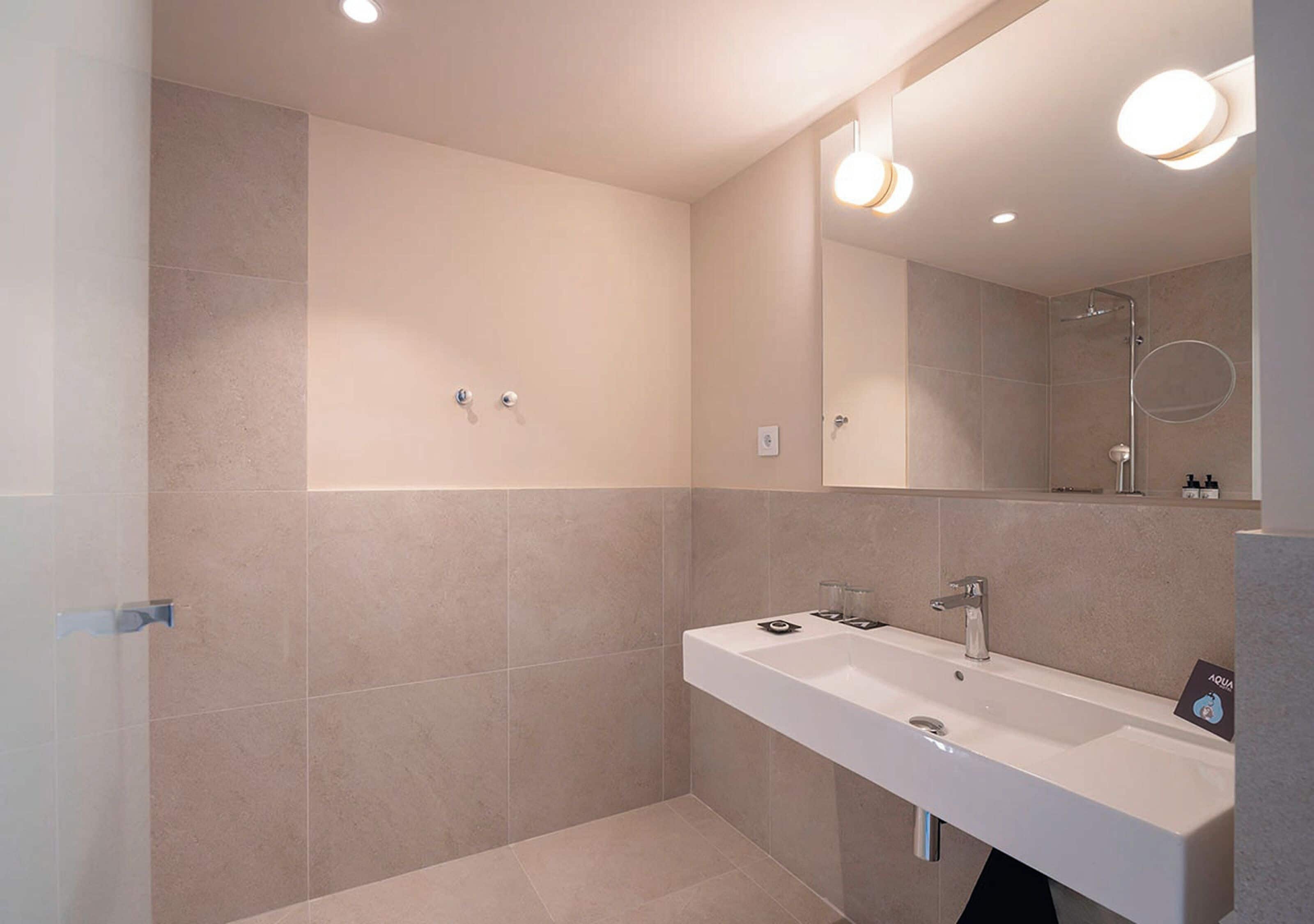 Une salle de bain moderne avec un grand miroir, deux lavabos et un espace douche.