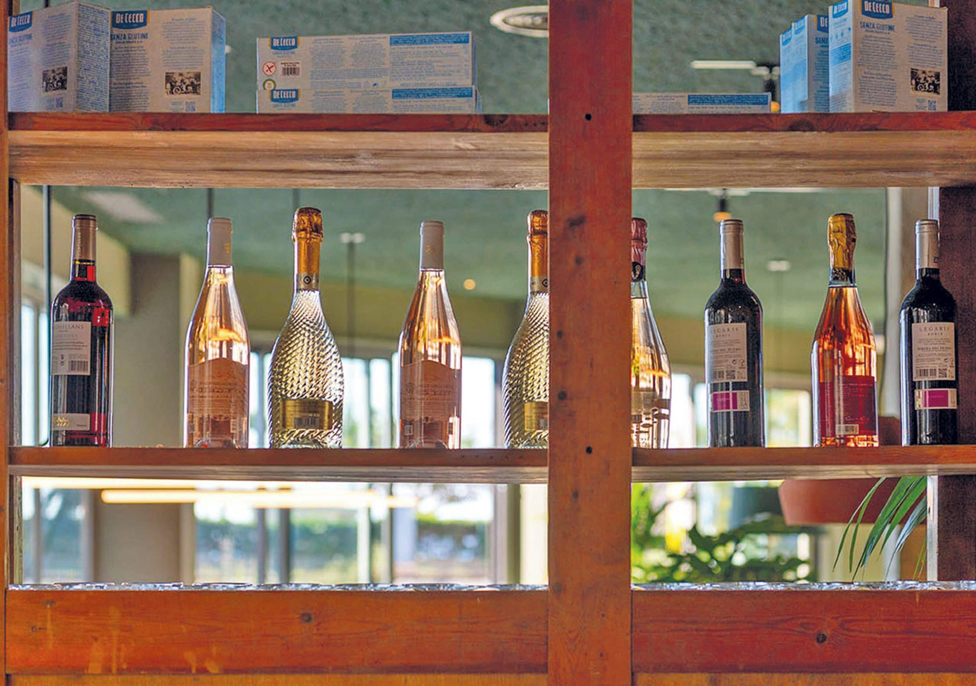 Un estante de madera con varias botellas de vino y una caja de pañuelos.