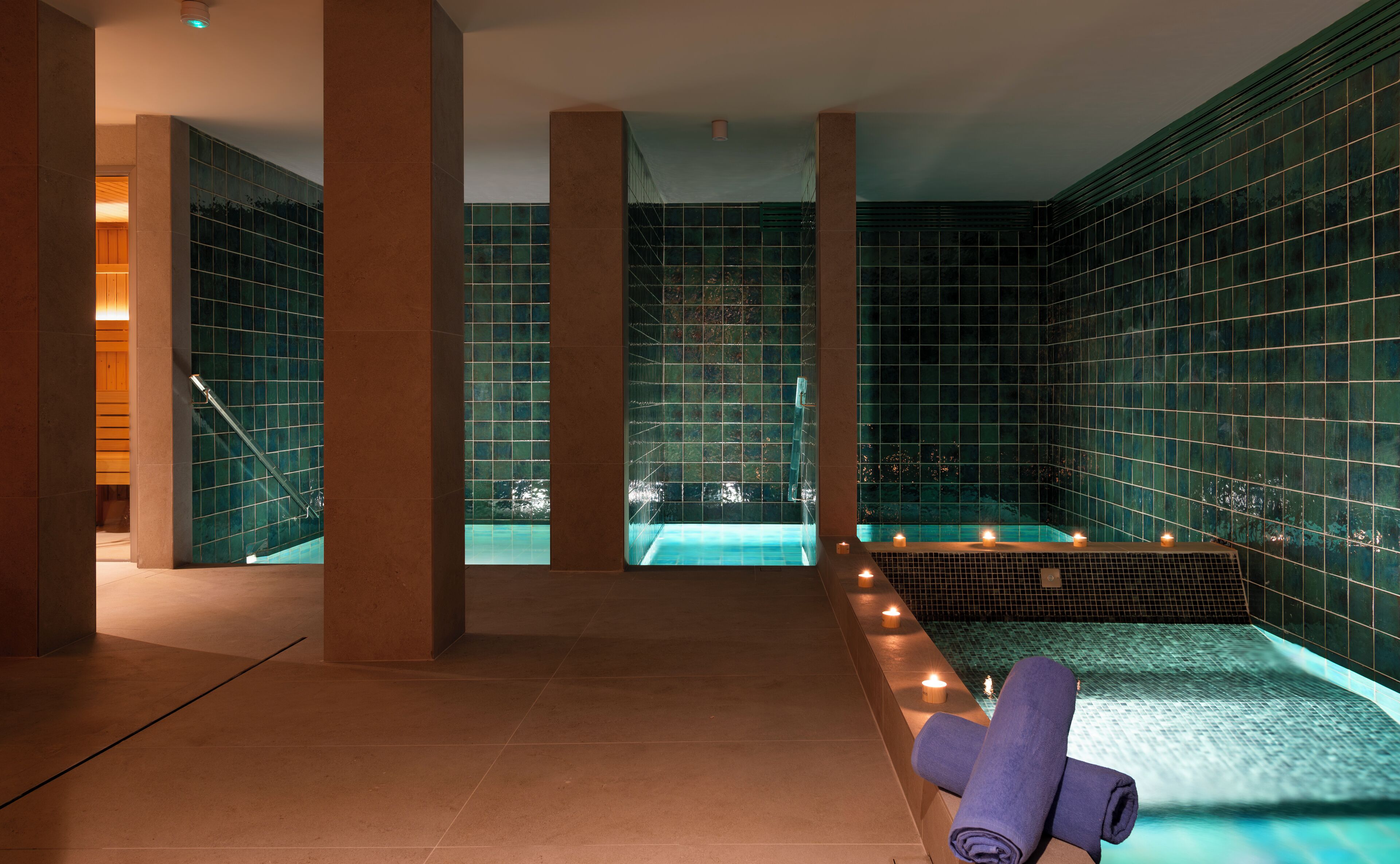 A spa area with a hot tub, tiled walls, and a towel on a bench.