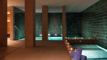 Zona de spa con jacuzzi, paredes de azulejos y una toalla en un banco.