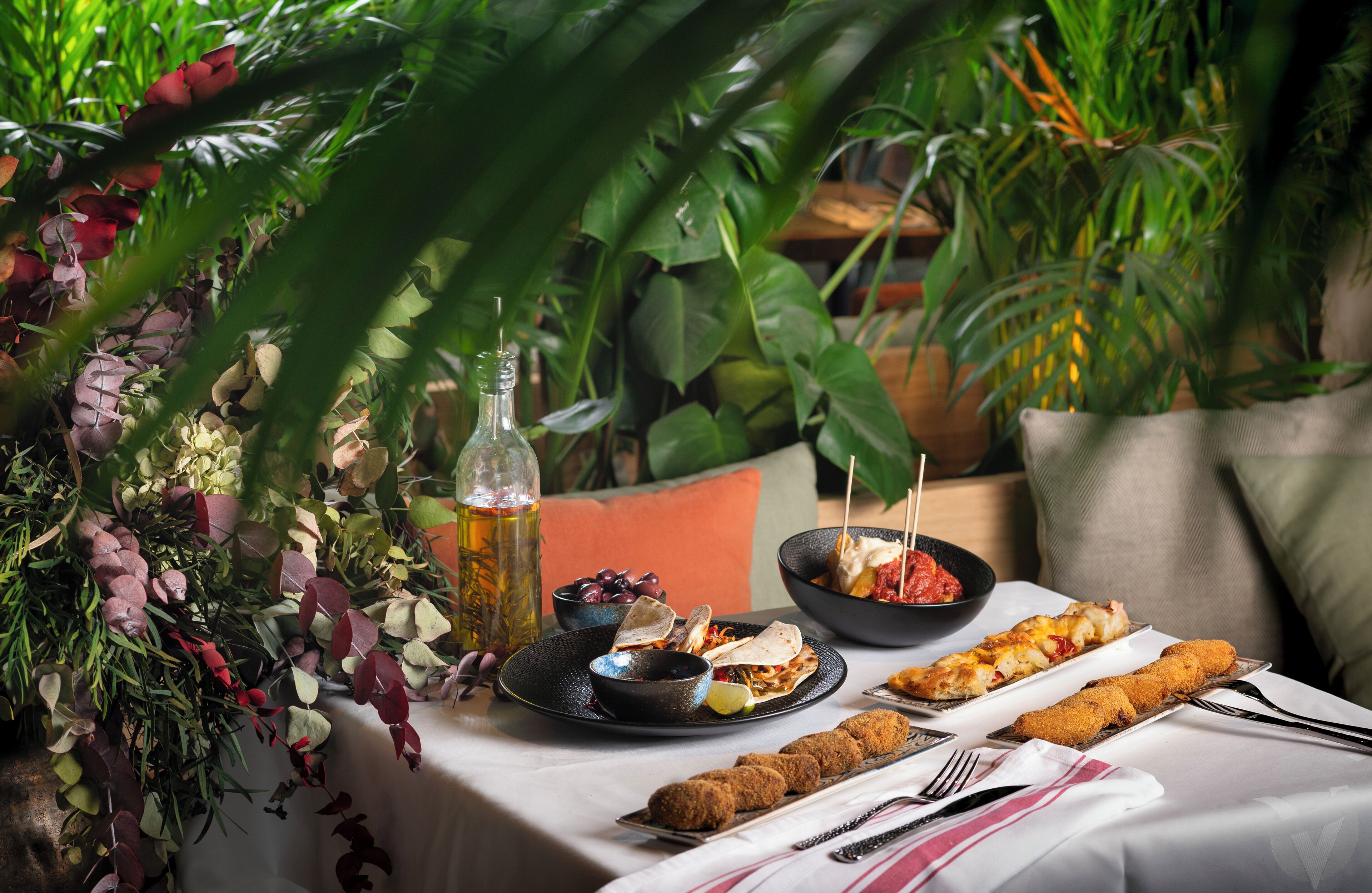 A table set with various dishes, a bottle of beer, and a potted plant in the background.