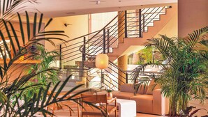 Un interior moderno con escalera, zona de estar y plantas en macetas.