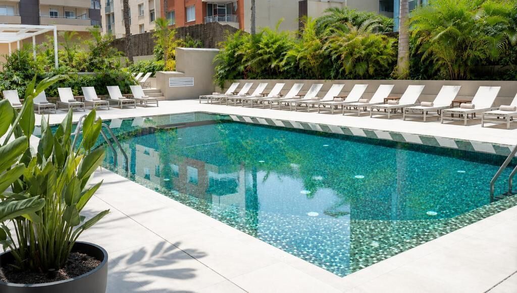 Una piscina al aire libre, sombrillas, sillones reclinables de piscina