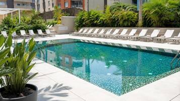 Una piscina al aire libre, sombrillas, sillones reclinables de piscina