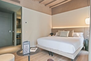 A hotel room with a large bed, bedside table, and a sign welcoming guests. - Andante Princesa (Barcelona)