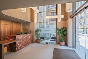 Una moderna recepción con mostrador de mármol, paneles de madera y plantas en macetas.