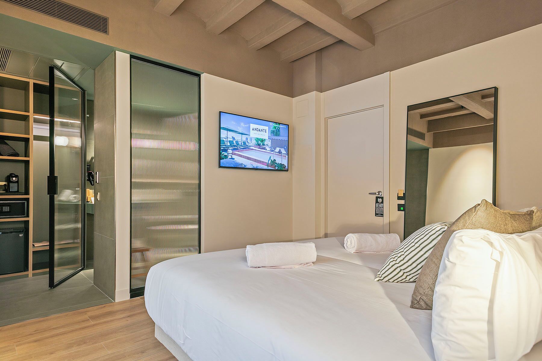Habitación de hotel con cama, televisión, espejo y puerta corrediza que da a un baño.
