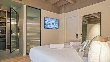 Habitación de hotel con cama, televisión, espejo y puerta corrediza que da a un baño.