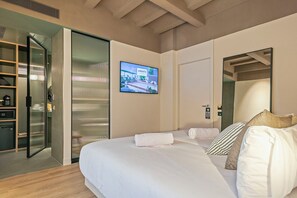 Habitación de hotel con cama, televisión, espejo y puerta corrediza que da a un baño.