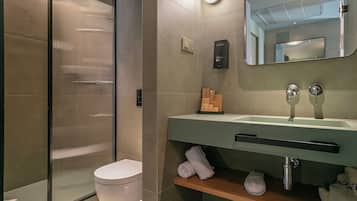Un baño moderno con cabina de ducha de vidrio, inodoro, lavabo con espejo y perchero para toallas.