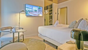 Habitación de hotel con cama, escritorio, silla, televisor y armario.