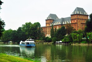 A large brick building with multiple towers and a river in the foreground.
