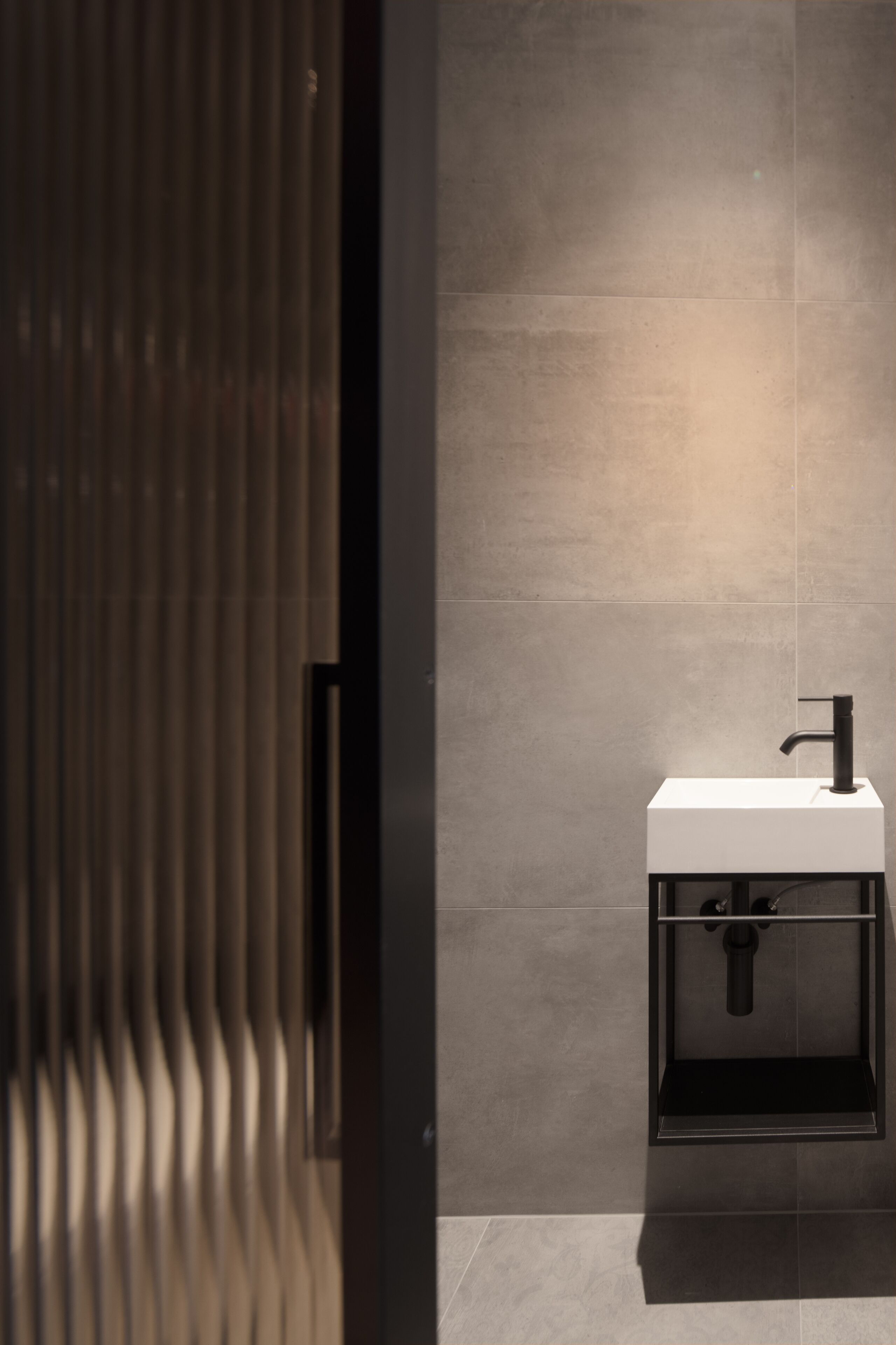A modern bathroom with a minimalist design, featuring a white sink and a black faucet.