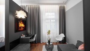 A modern living room with a fireplace, a dining area, and a seating area. - THE MANES Boutique Hotel Prague (Prague)