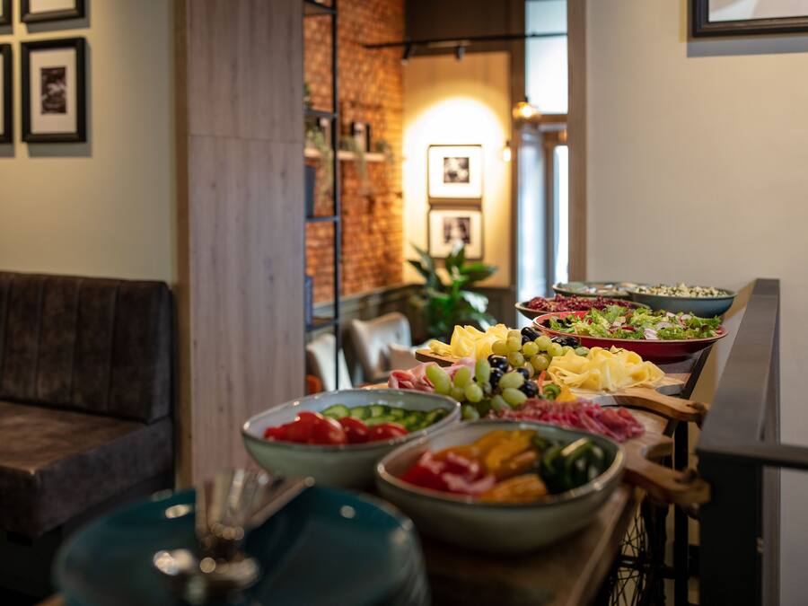 Un coin repas avec une variété de plats disposés sur une table, un canapé et des tableaux encadrés accrochés au mur.