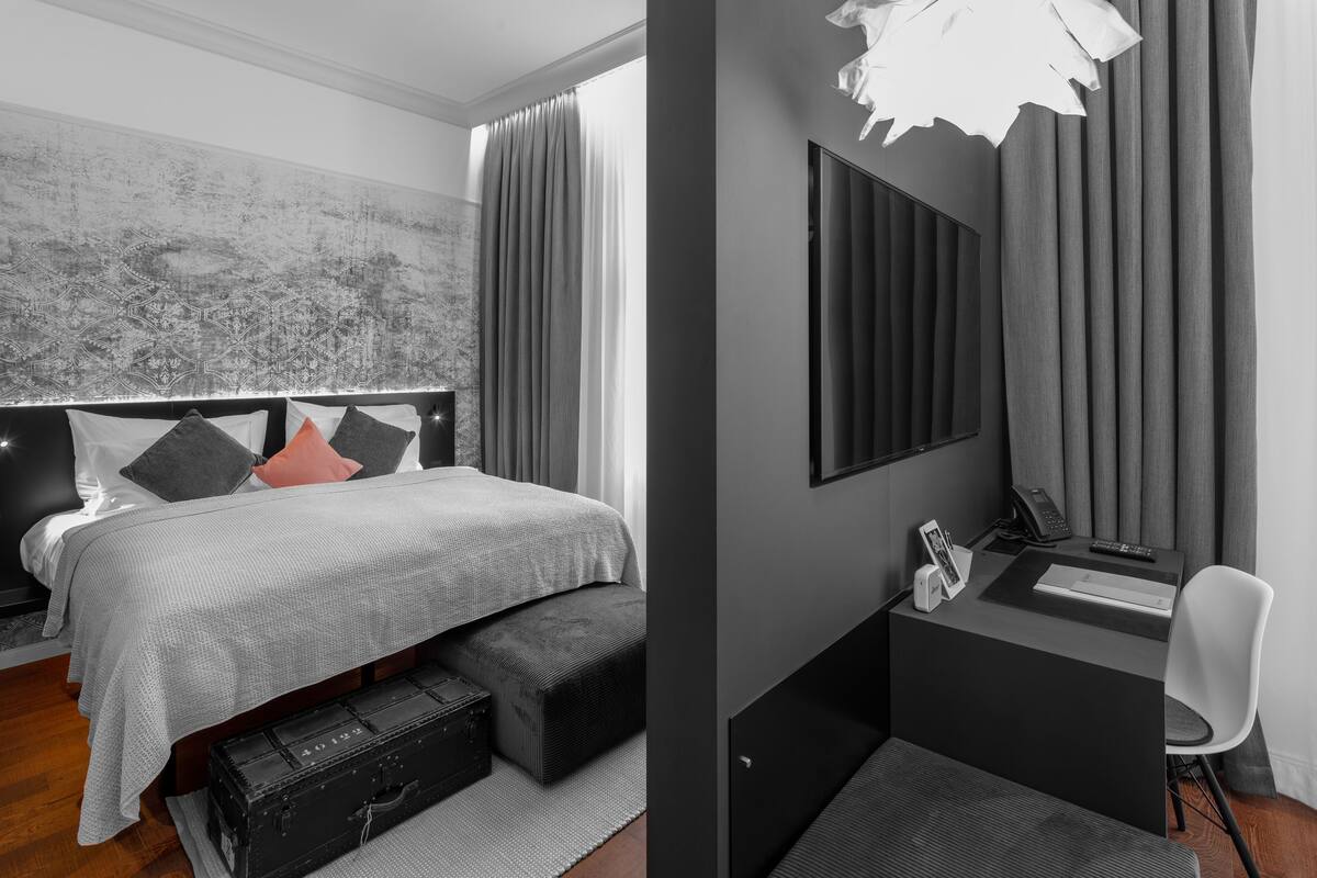 Un dormitorio moderno con cama, mesita de noche y zona de escritorio.