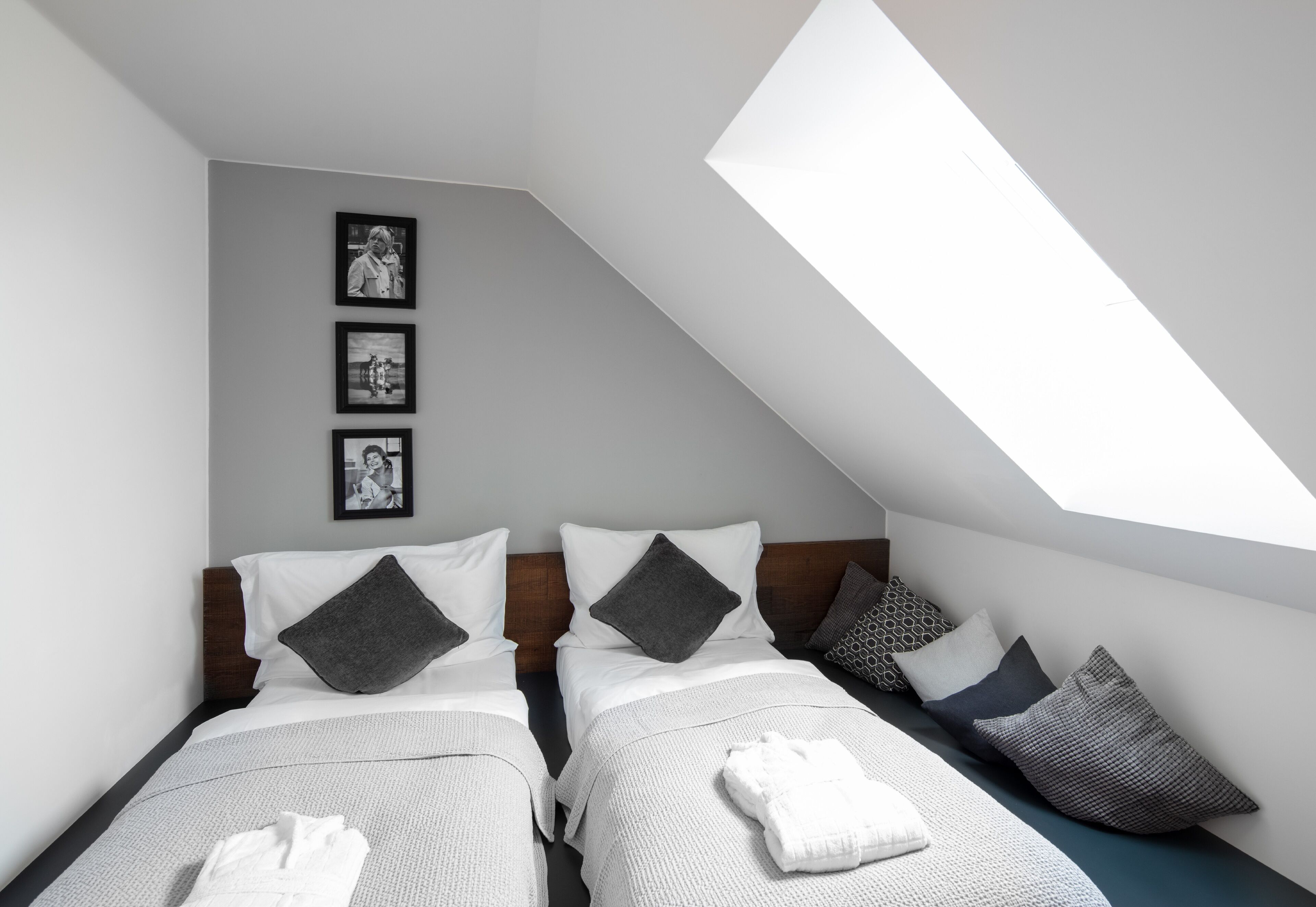 Ein modernes Hotelzimmer mit zwei Betten, einer schrägen Decke und einem Dachfenster.