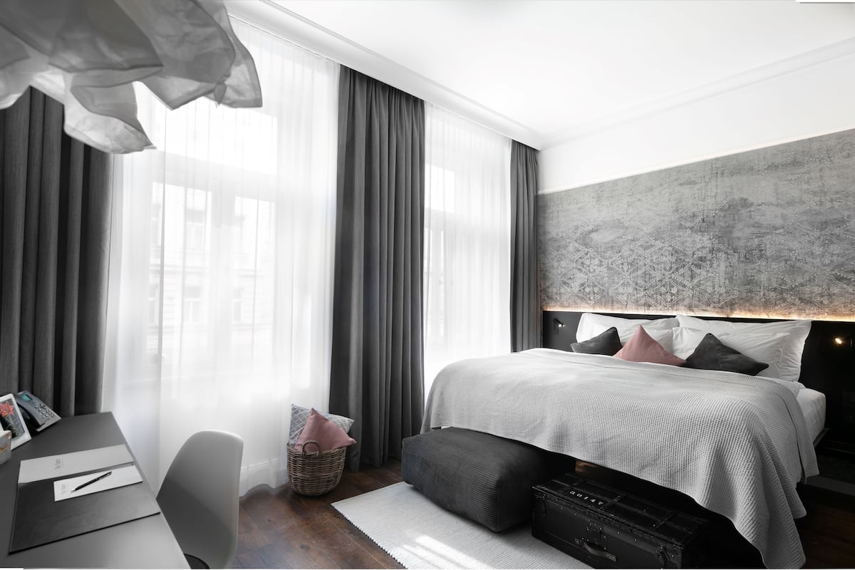 Un dormitorio moderno con una cama grande, un escritorio con computadora y un ventanal con cortinas.