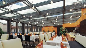A restaurant with long tables, chairs, and a glass ceiling. - EA Hotel Crystal Palace (Prague)