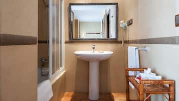 A bathroom with a sink, mirror, shower, and a wicker basket with toiletries.