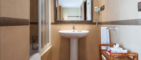 A bathroom with a sink, mirror, shower, and a wicker basket with toiletries.