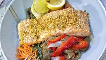 Un plato con un filete de salmón, espárragos, pimientos rojos y rodajas de limón.