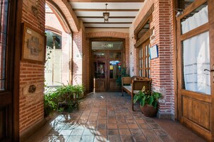 Un pasillo de hotel con paredes de ladrillo, bancos de madera y plantas en macetas.