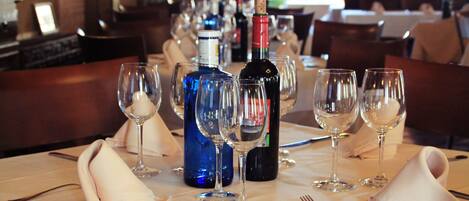 Una mesa puesta con copas de vino, una botella y cubiertos.