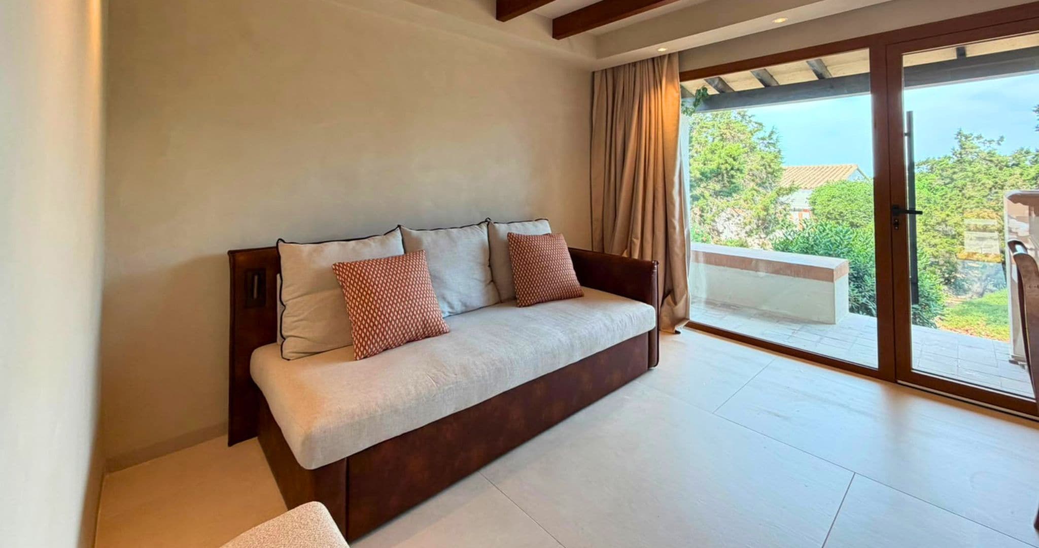 Una sala de estar moderna con un sofá, vistas al exterior a través de una puerta corrediza de vidrio y un techo de madera.