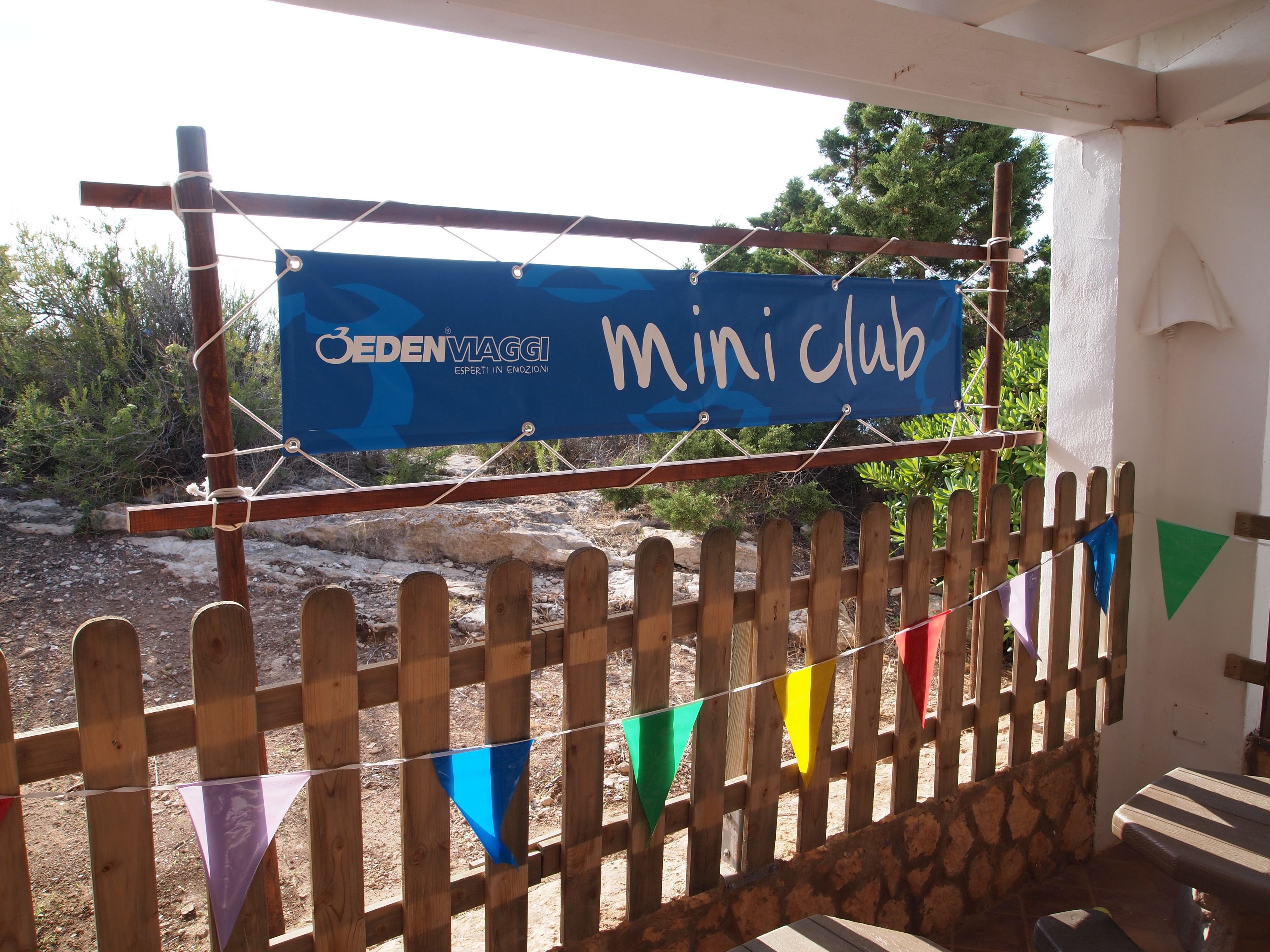 A wooden fence with colorful triangular flags and a blue banner hanging above it.