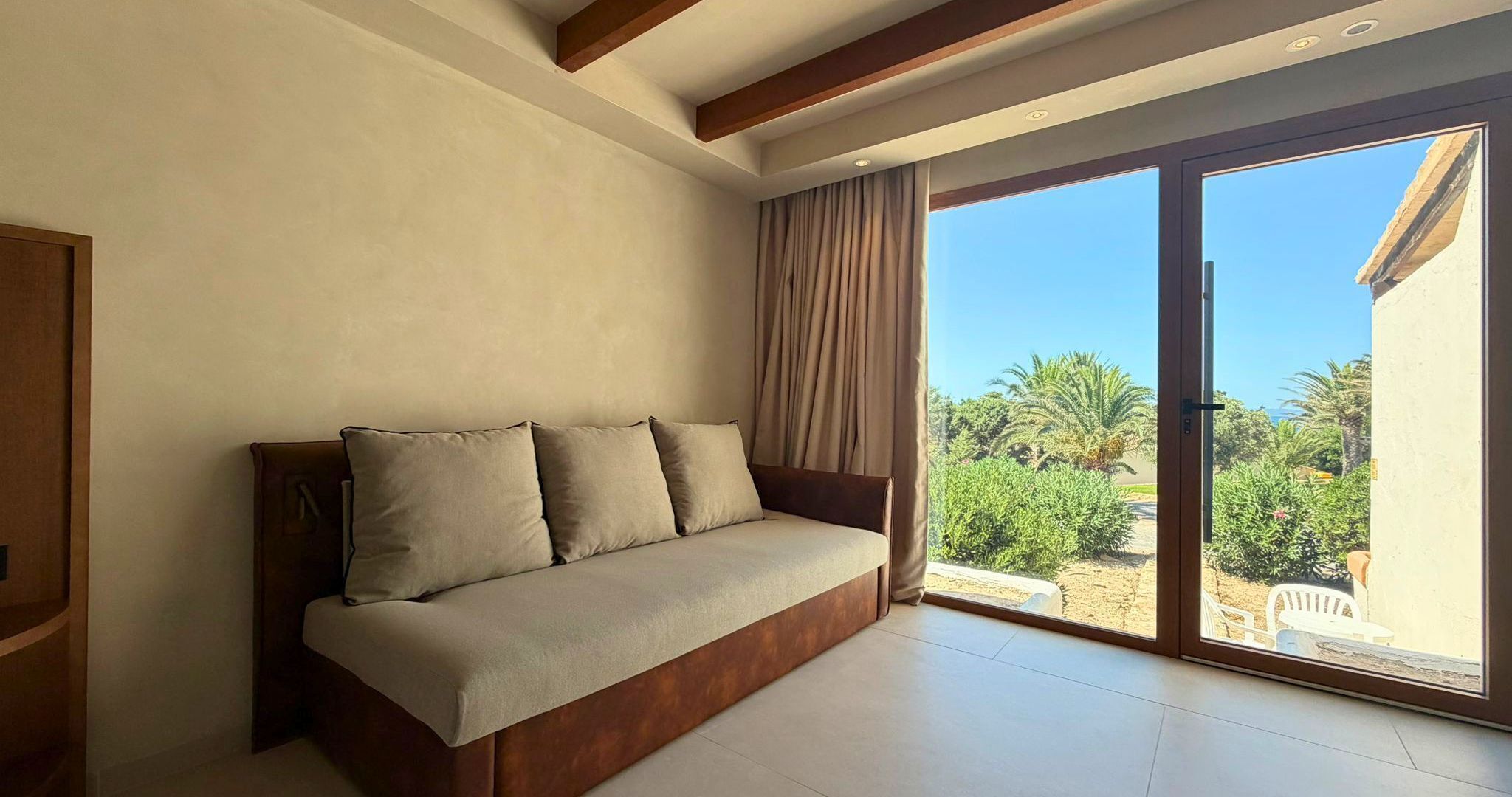 Quarto moderno com sofá, uma grande porta de vidro deslizante e vista para o verde lá fora.