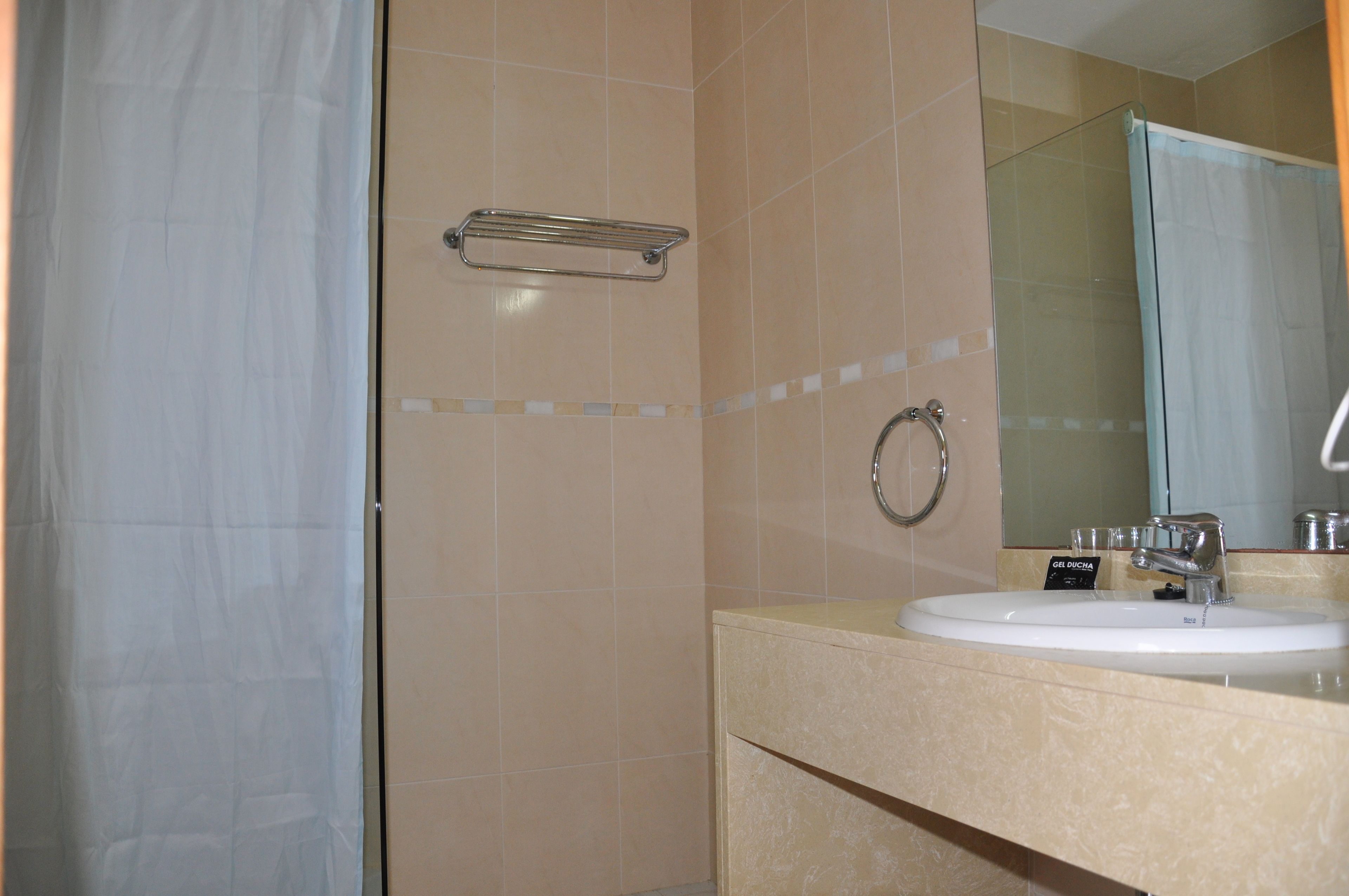 A bathroom with a sink, mirror, and towel rack.