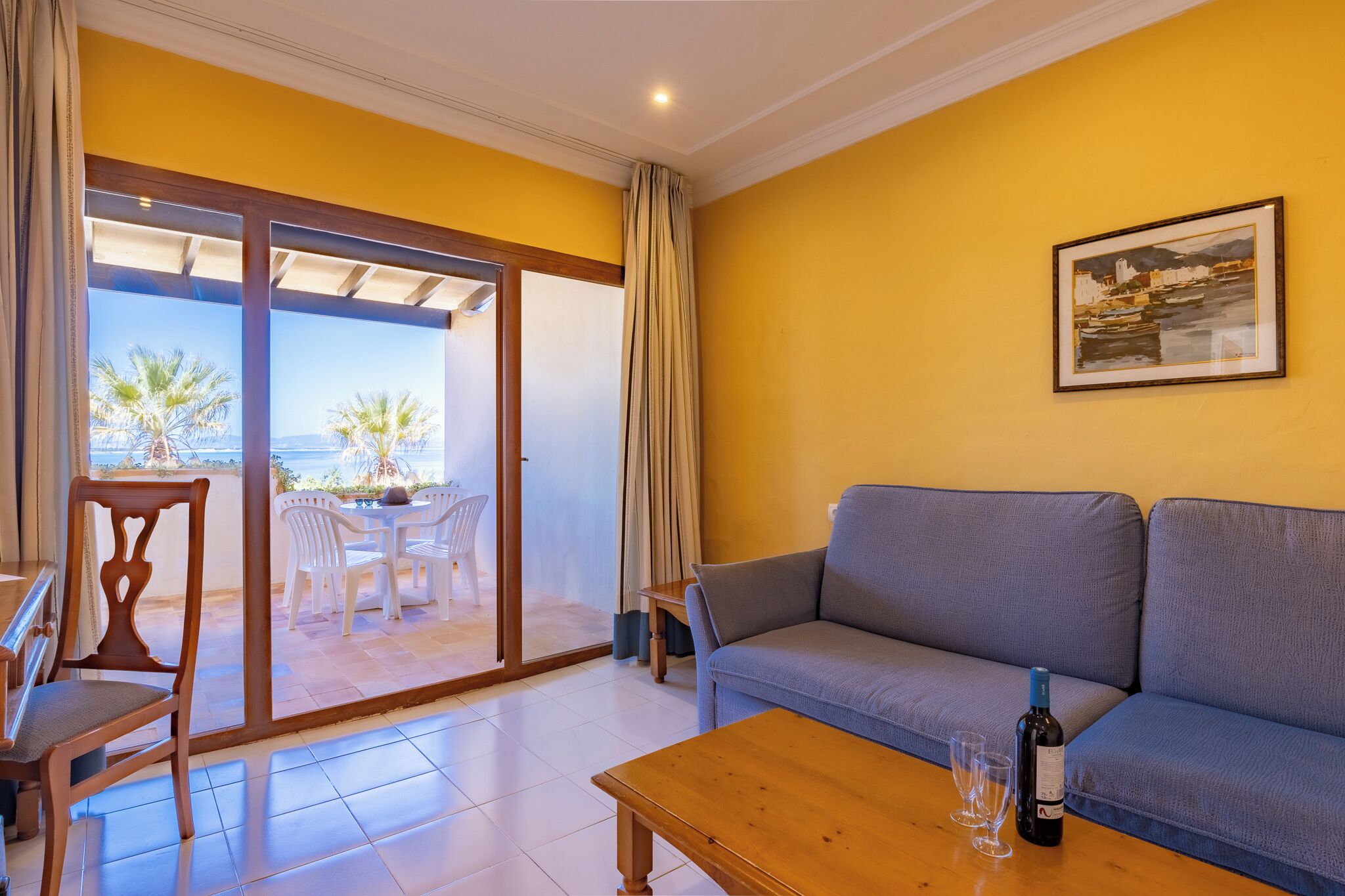 A living room with a sofa, a wooden table, and a glass of wine.