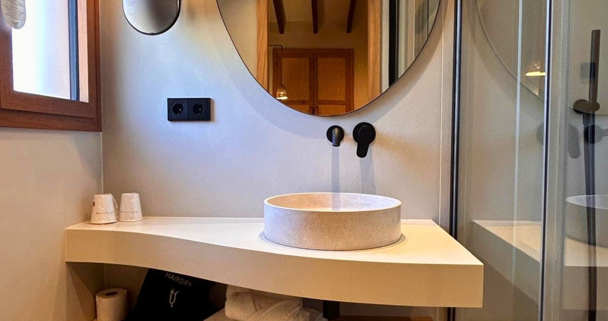 Un baño con un lavabo redondo, un espejo y un perchero para toallas.