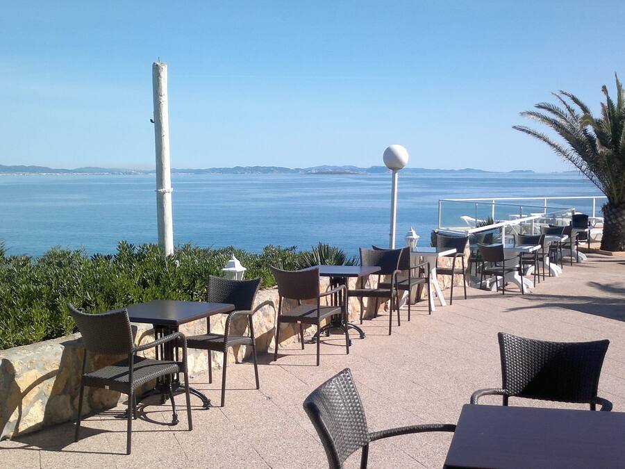 Un espacio al aire libre con mesas y sillas con vistas al mar.