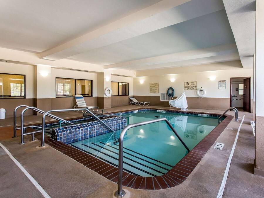 Piscina com deck ladrilhado, grades de metal e placa indicando 'proibido mergulhar'.