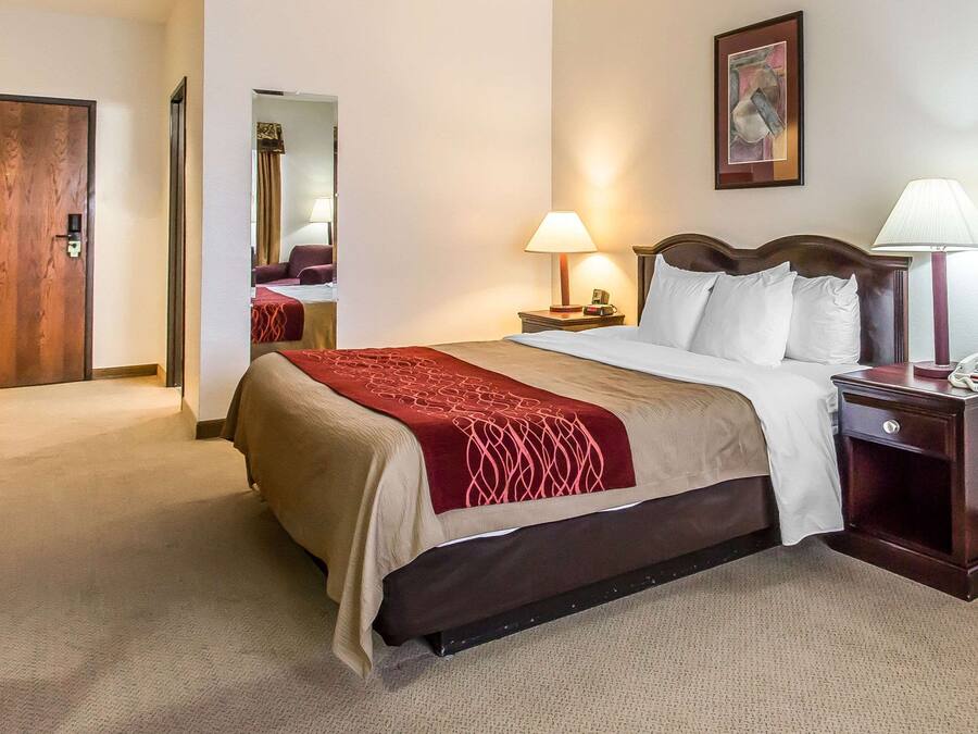 Une chambre d’hôtel avec un lit, des lampes de chevet, une table de chevet, une porte en bois et un miroir.